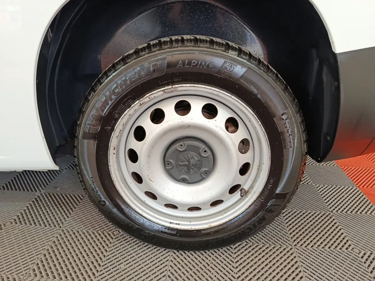 Gros plan sur la roue avant gauche du Peugeot Partner blanc, jante acier avec pneu Michelin Alpin 6.