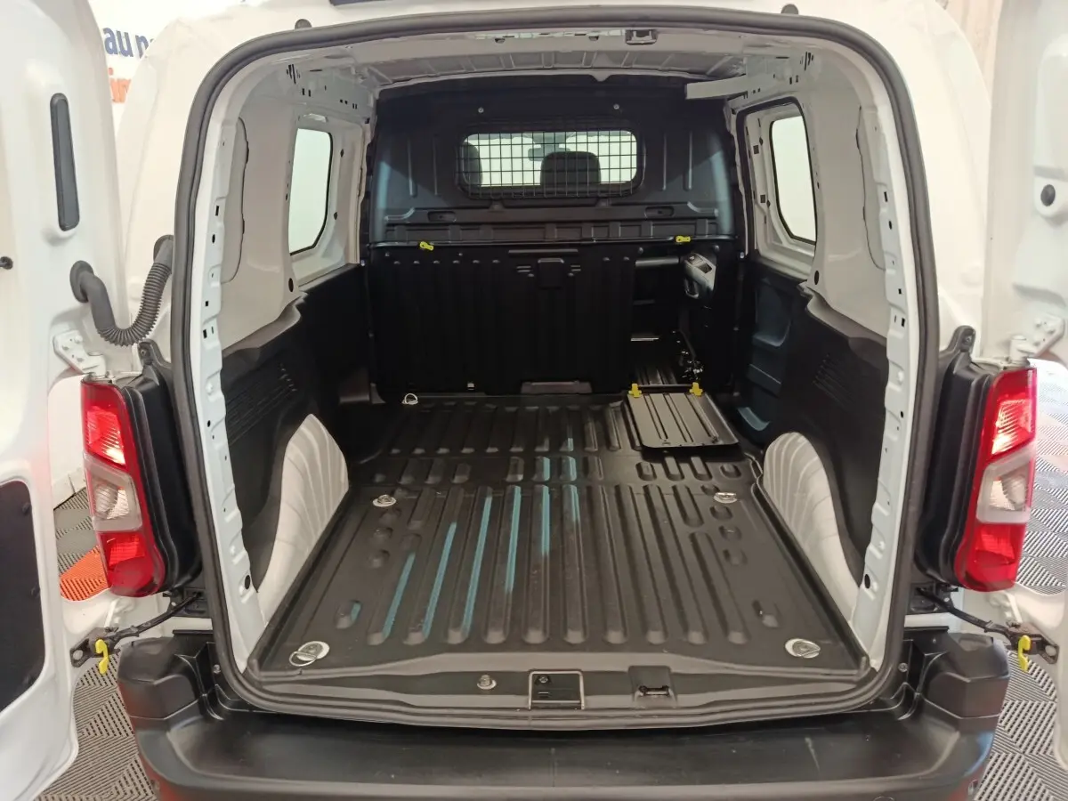 Vue arrière du coffre blanc du Peugeot Partner 2021, montrant l'espace de chargement vide avec cloison pleine noire.
