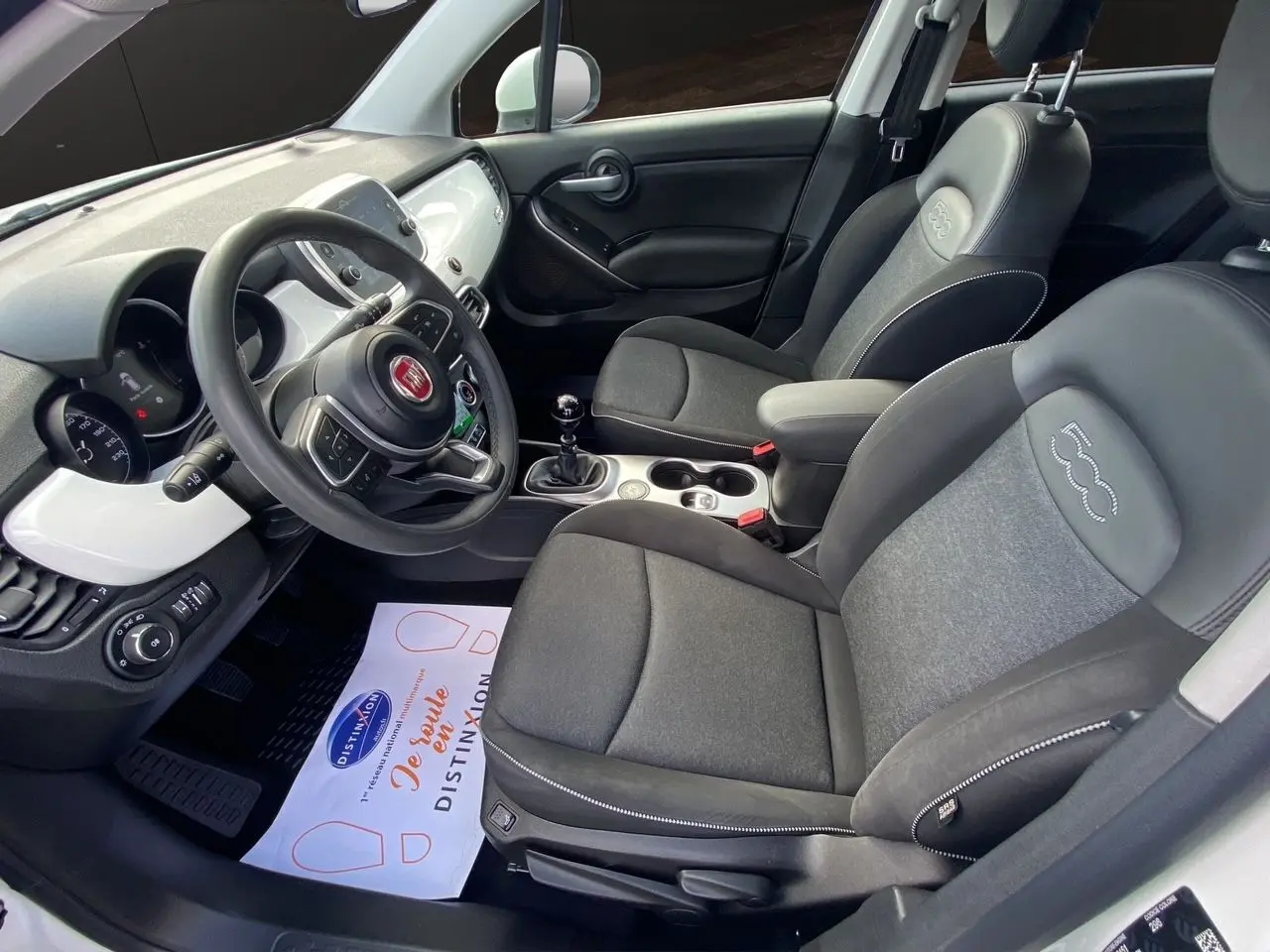 Intérieur noir du Fiat 500X 2018 vu côté conducteur, avec volant multifonction et sièges tissu et cuir embossés 500.