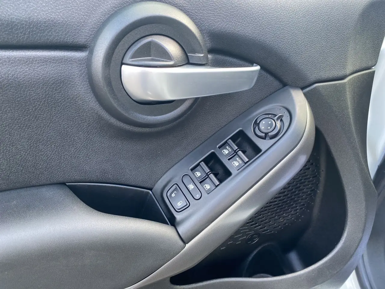 Poignée de porte intérieure côté gauche noire avec commandes électriques des vitres sur FIAT 500X blanc 2018.