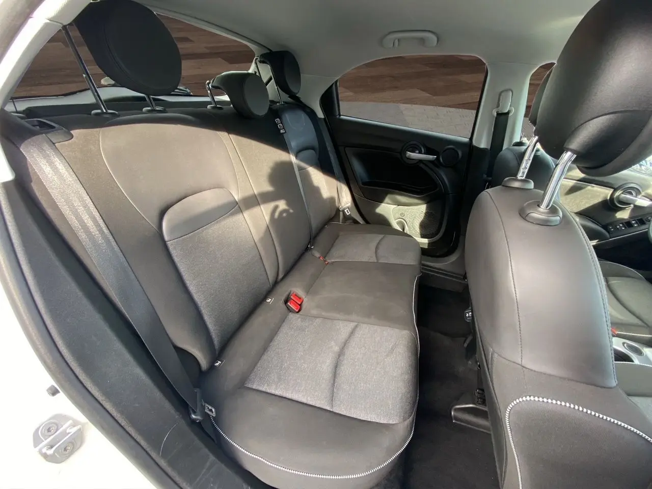 Vue intérieure arrière du Fiat 500X blanc de 2018, montrant les sièges arrière en tissu noir avec surpiqûres blanches.