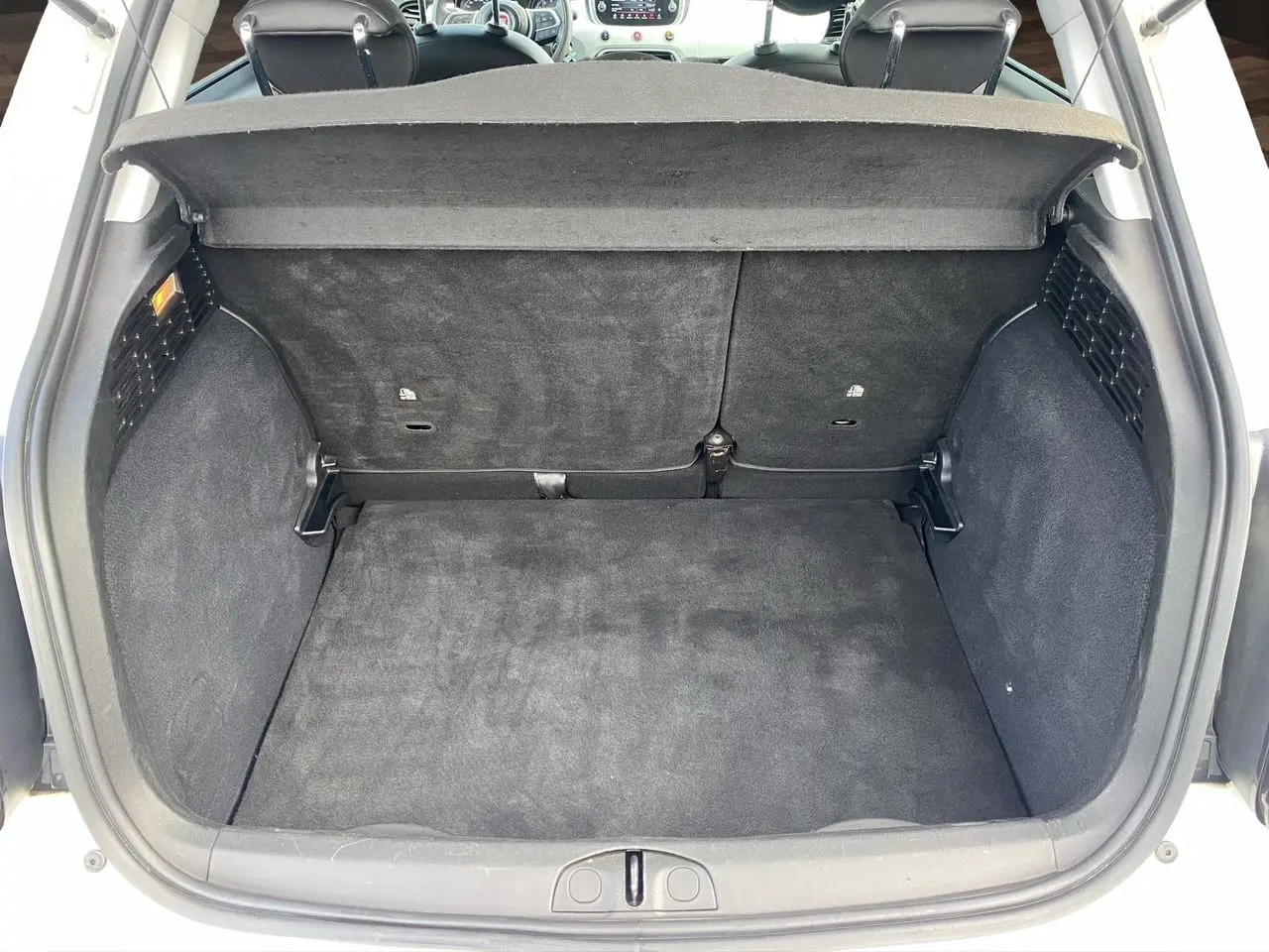 Vue arrière du coffre noir spacieux de la FIAT 500X blanche, avec banquette arrière et cache-bagages visibles.