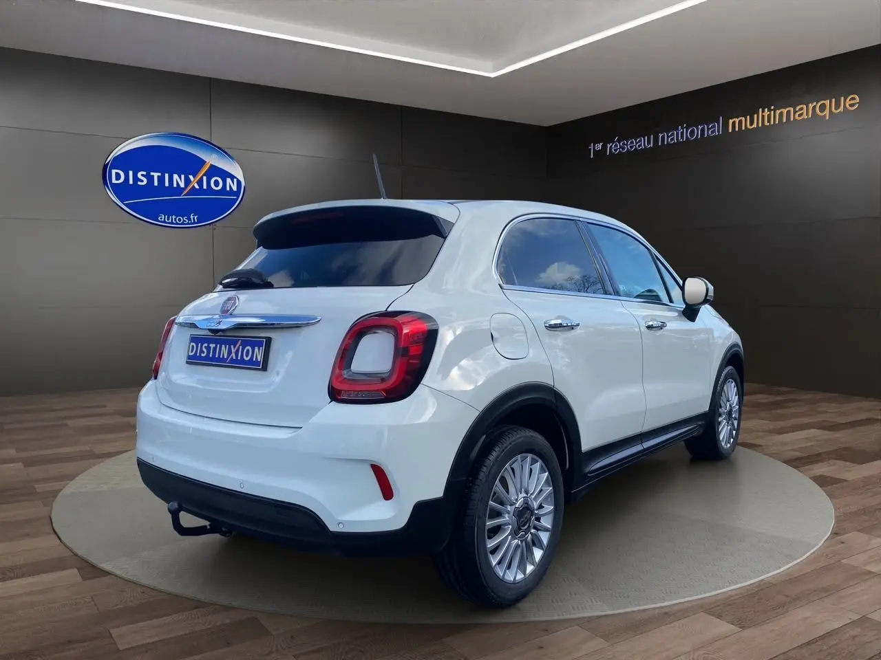 Vue 3/4 arrière droite d'un FIAT 500X blanc avec jantes alliage et feux arrière LED dans un showroom.