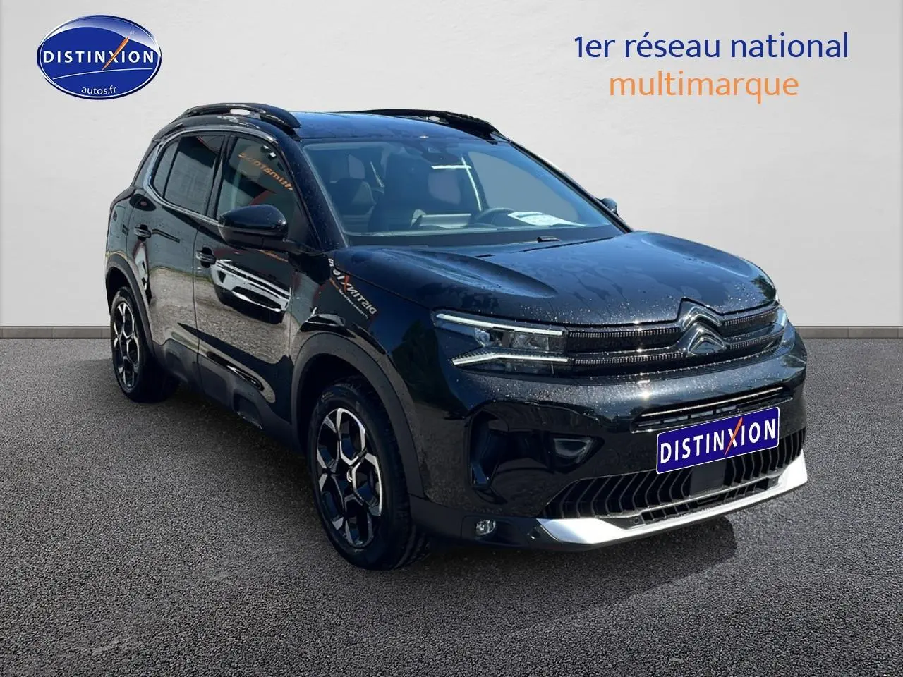 Citroën C5 Aircross noir en 3/4 avant droit avec barres de toit et jantes alu 18 pouces visibles.