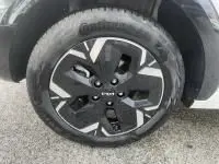 Gros plan sur la roue avant droite d’une KIA Niro EV 204 CV Active blanche 2024, avec jante noire et argentée au design moderne.