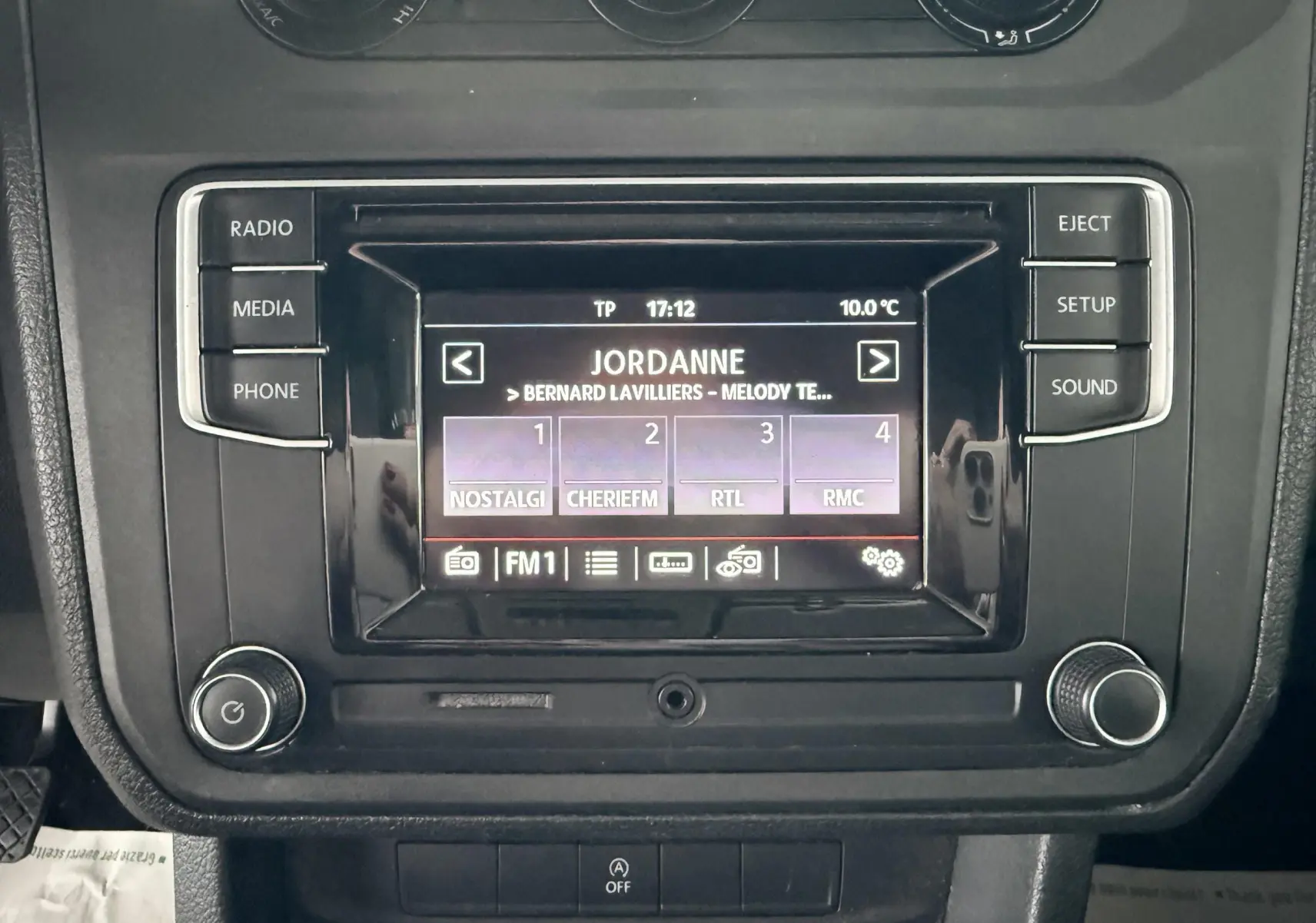 Gros plan sur l’écran multimédia noir du Volkswagen Caddy Maxi Long 2017 affichant une radio FM avec plusieurs stations.