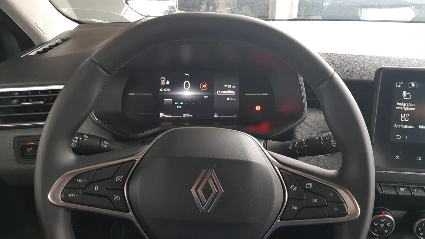 Vue intérieure centrée sur le volant noir de la Renault Clio 2025 avec tableau de bord numérique et écran tactile.
