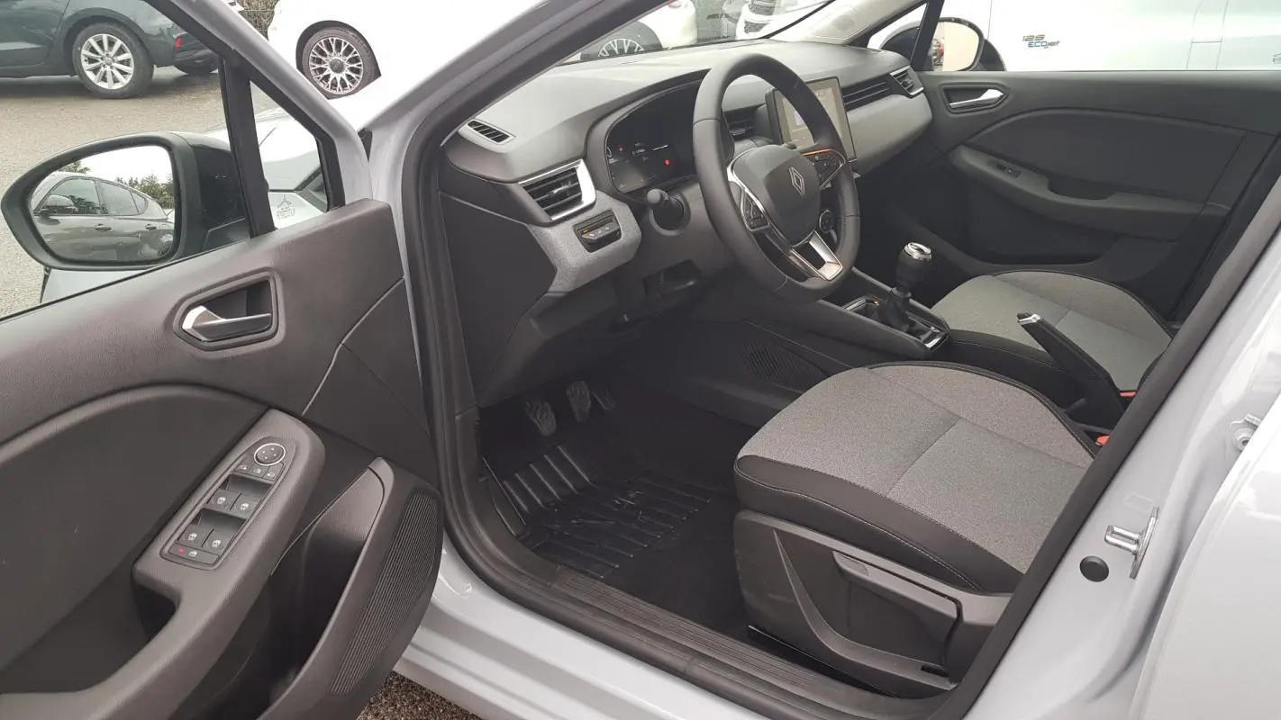 Intérieur côté conducteur de la Renault Clio gris 2025, vue sur tableau de bord, volant et sièges tissu bicolore.