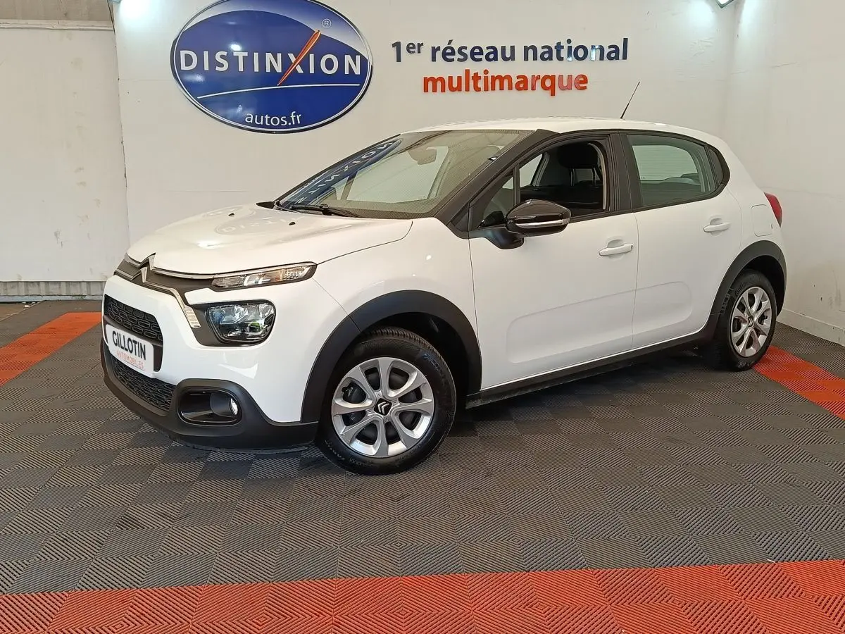 Citroën C3 blanche vue 3/4 avant droit en intérieur, avec phares LED et jantes alliage distinctives.
