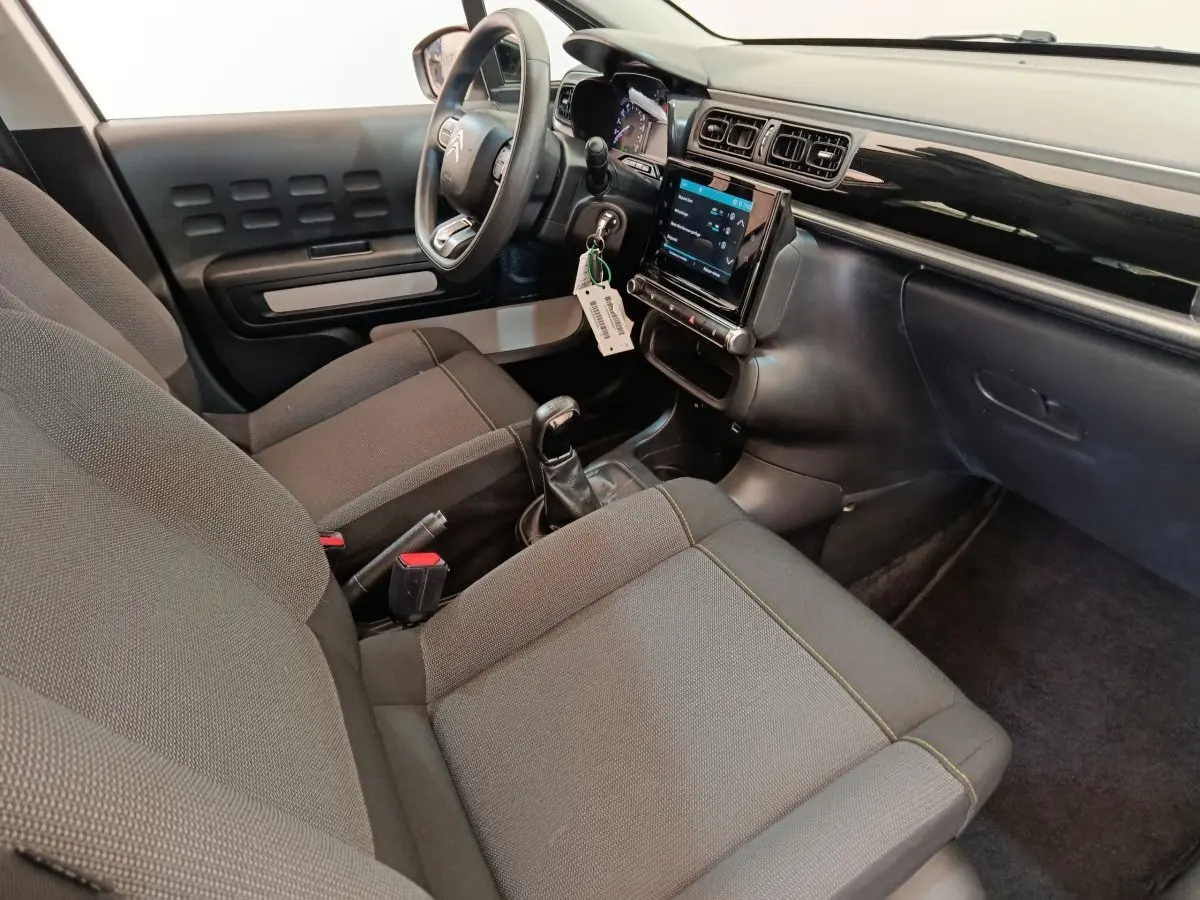 Intérieur de la Citroën C3 2022 vu côté conducteur, sièges gris, volant multifonctions et écran tactile central.