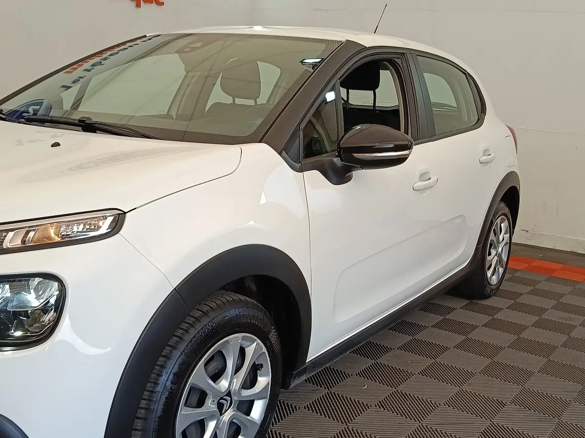 Citroën C3 blanche vue 3/4 avant droit, avec rétroviseur noir et jantes alliage distinctives.