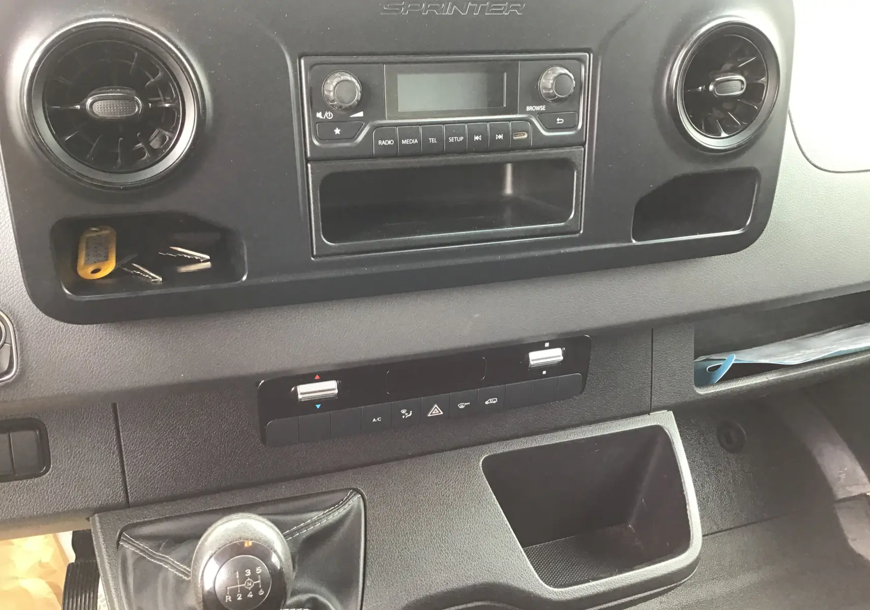 Vue rapprochée de la console centrale intérieure noire du Mercedes Sprinter blanc, avec levier de vitesses manuel visible.