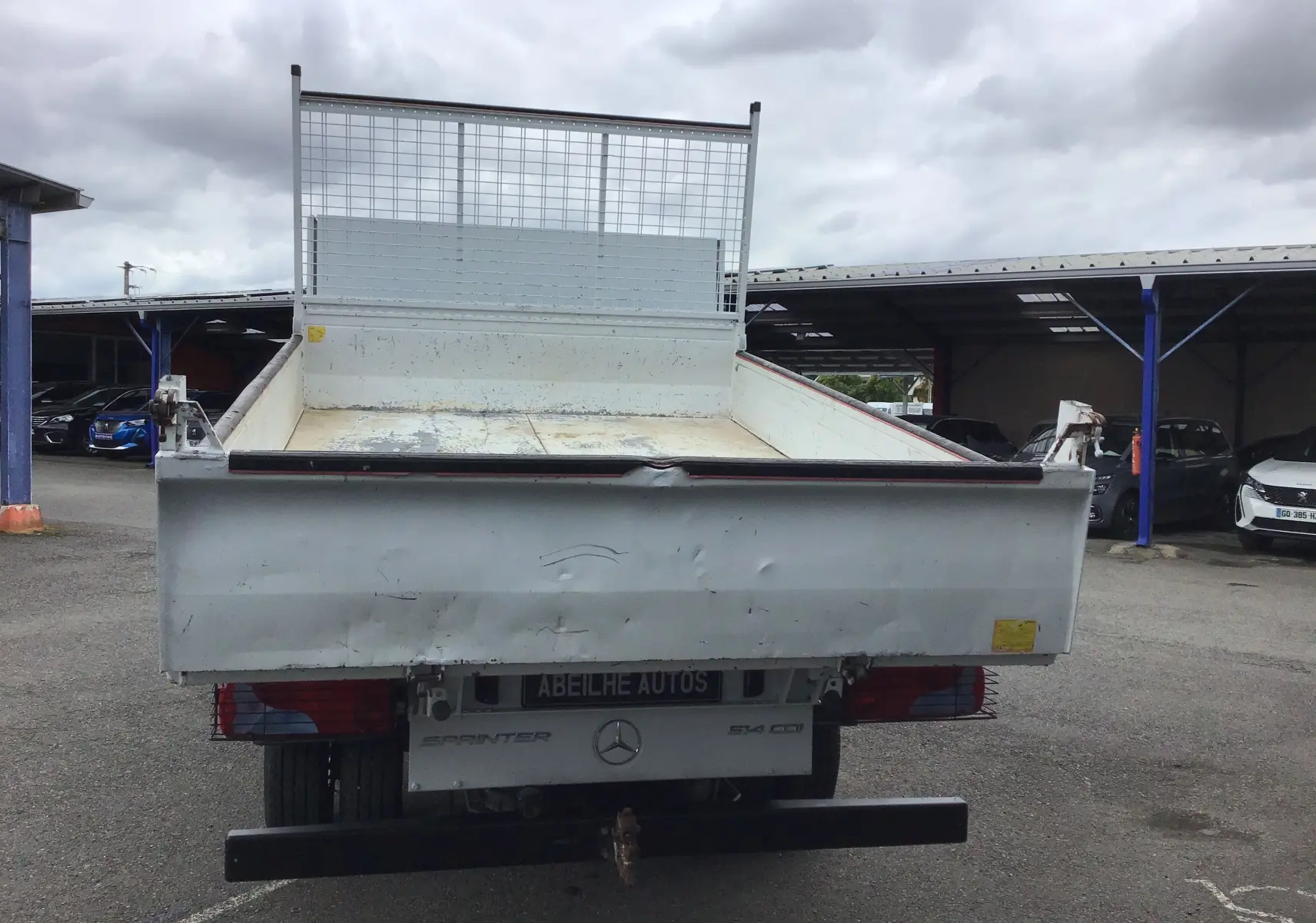 Vue arrière d'un utilitaire Mercedes Sprinter blanc avec benne 3 mètres et coffre, plateau ouvert et ridelles métalliques.