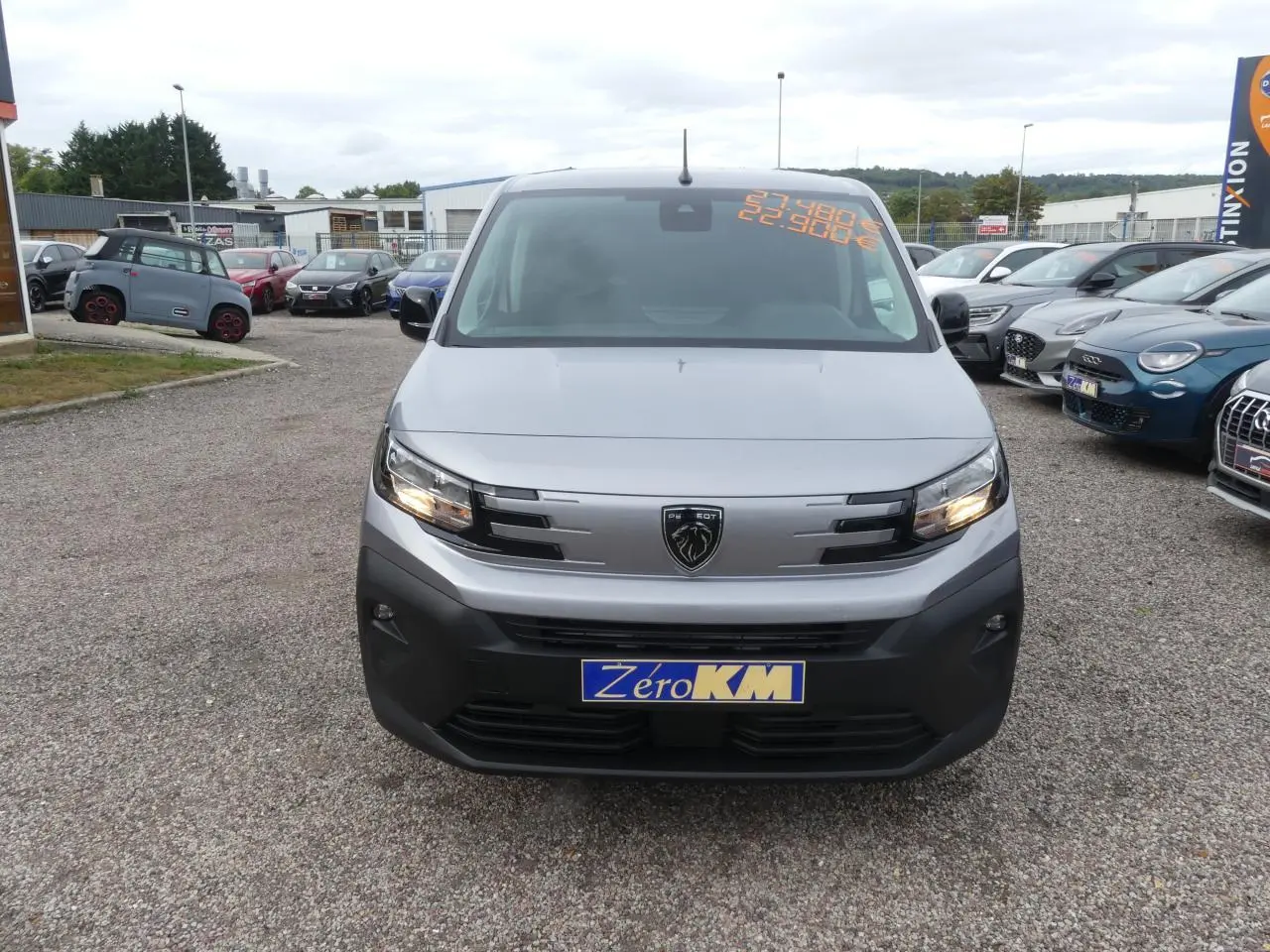 Vue de face du Peugeot Partner gris métallisé 2025 avec calandre noire et plaque Zéro KM visible.