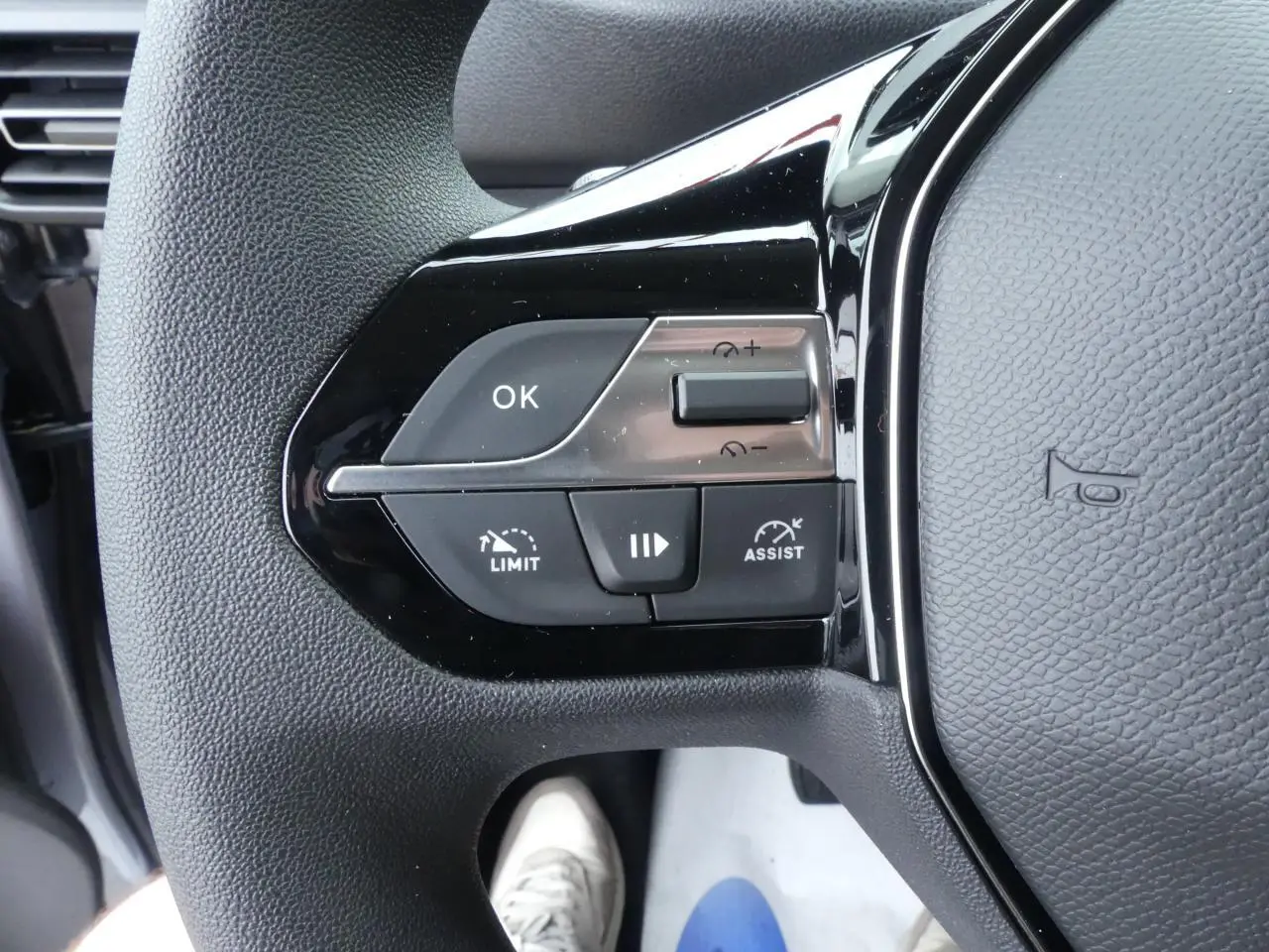 Gros plan sur les commandes à gauche du volant du Peugeot Partner gris métallisé 2025, boutons multifonctions visibles.