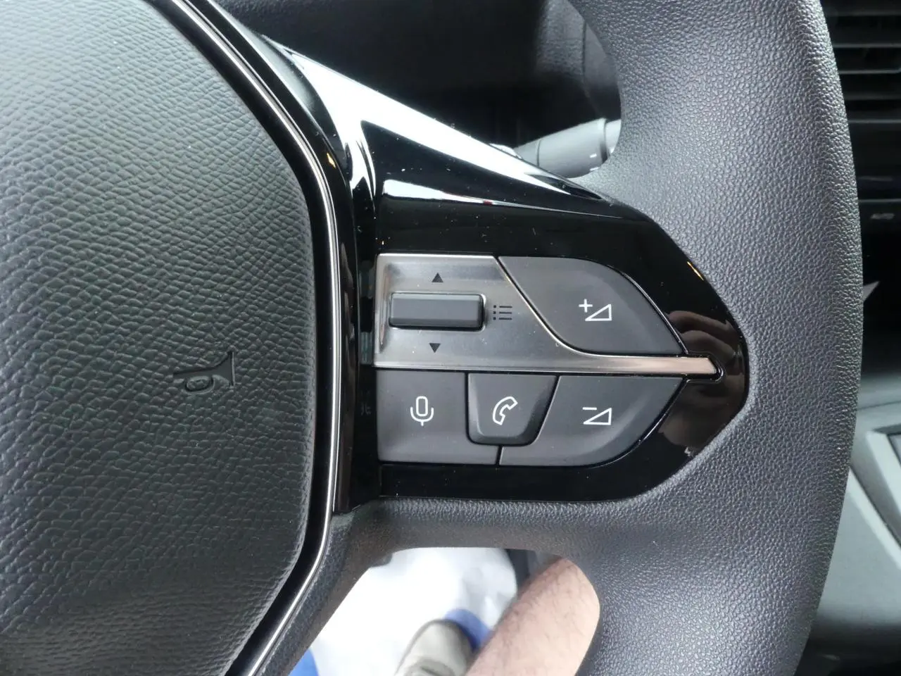 Gros plan sur les commandes du volant noir du Peugeot Partner XL 2025, boutons de volume et appel téléphonique visibles.