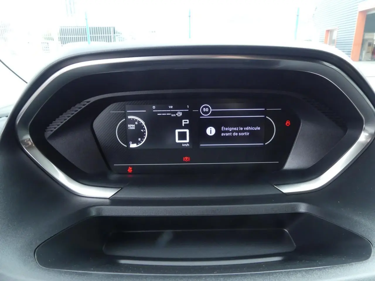Tableau de bord numérique du Peugeot Partner 2025 affichant un message d'arrêt du véhicule, vue frontale rapprochée.