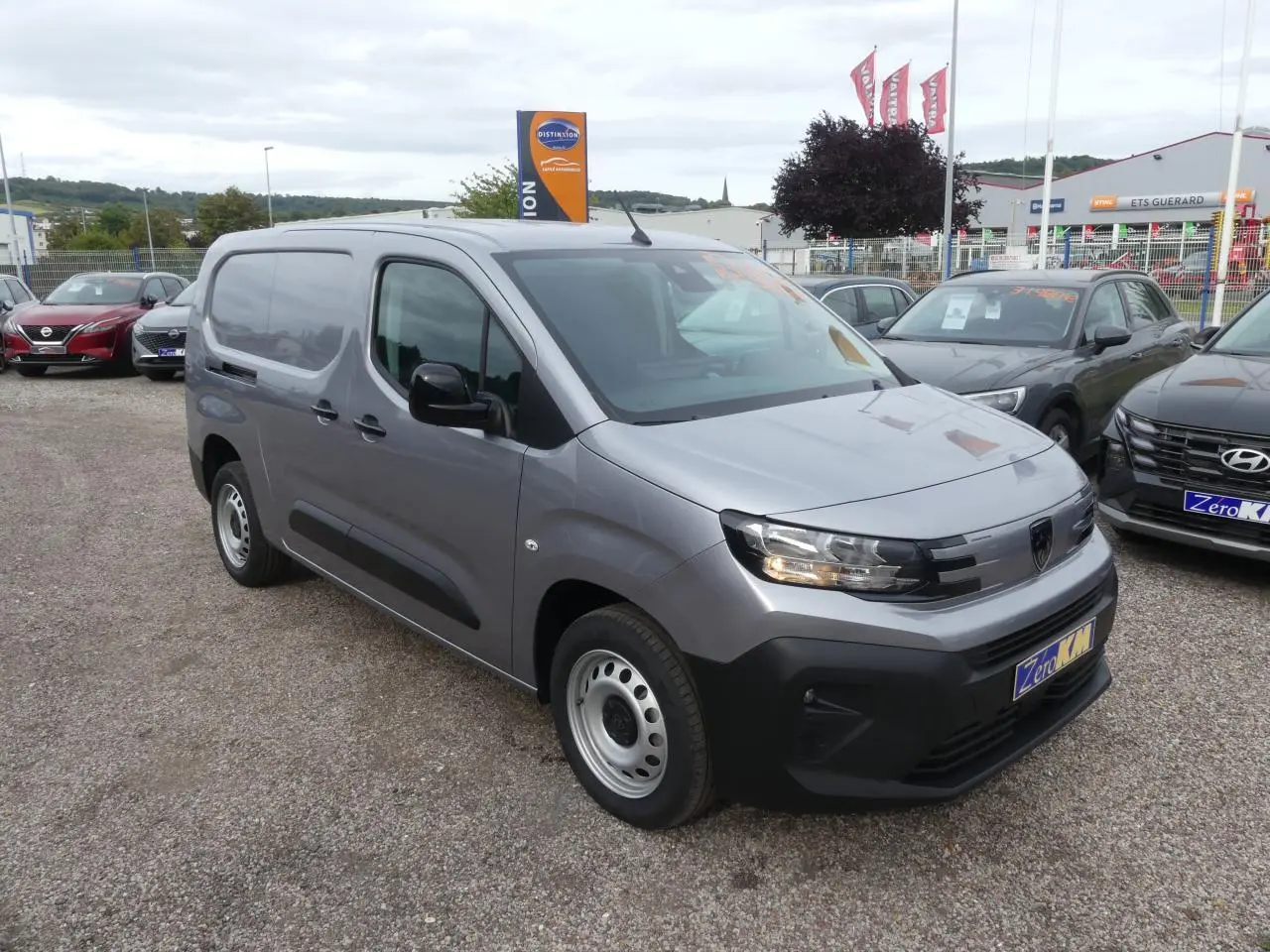 Peugeot Partner XL gris métallisé en 3/4 avant droit, fourgon utilitaire avec jantes tôle et calandre noire.