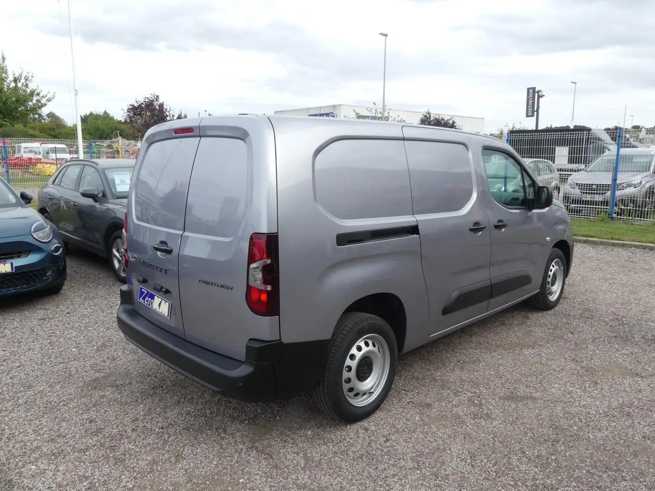Vue 3/4 arrière droite d'un Peugeot Partner gris métallisé avec portes arrière battantes et jantes tôle 16 pouces.