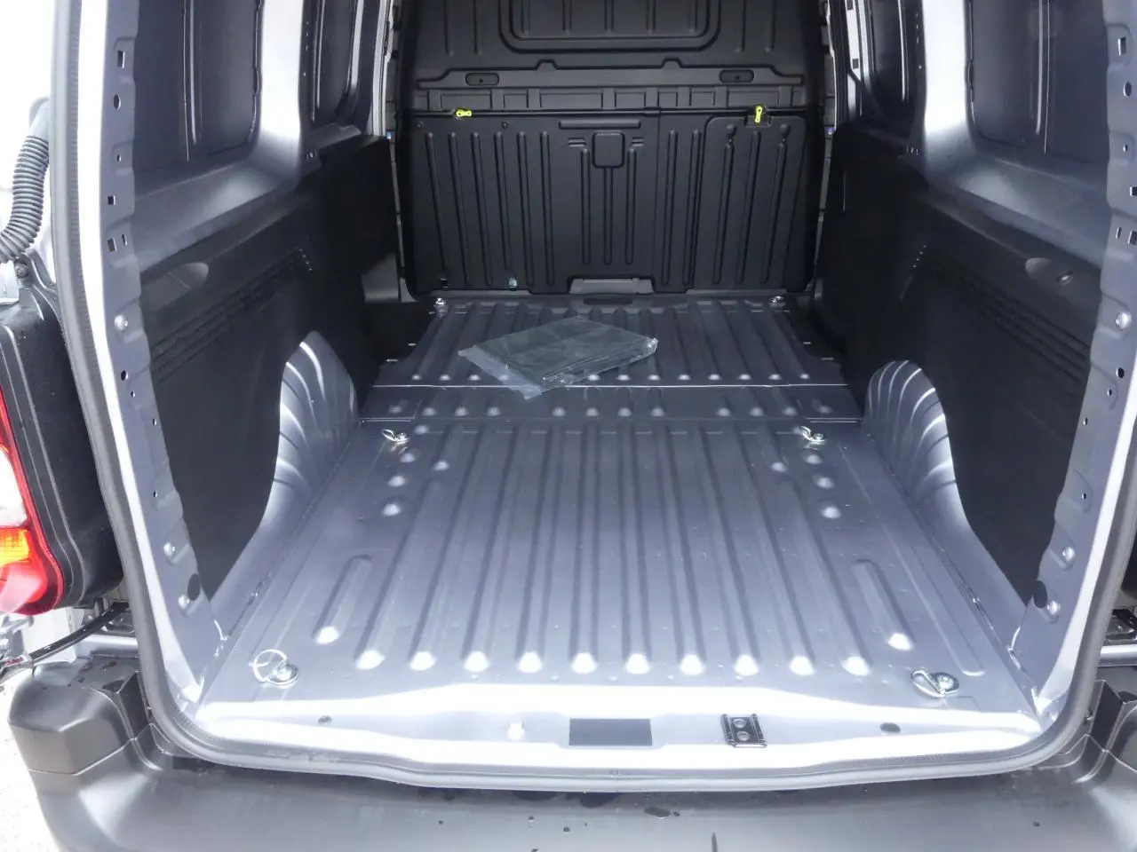 Vue intérieure du coffre du Peugeot Partner XL gris métallisé, montrant le plancher et les anneaux d'arrimage au sol.