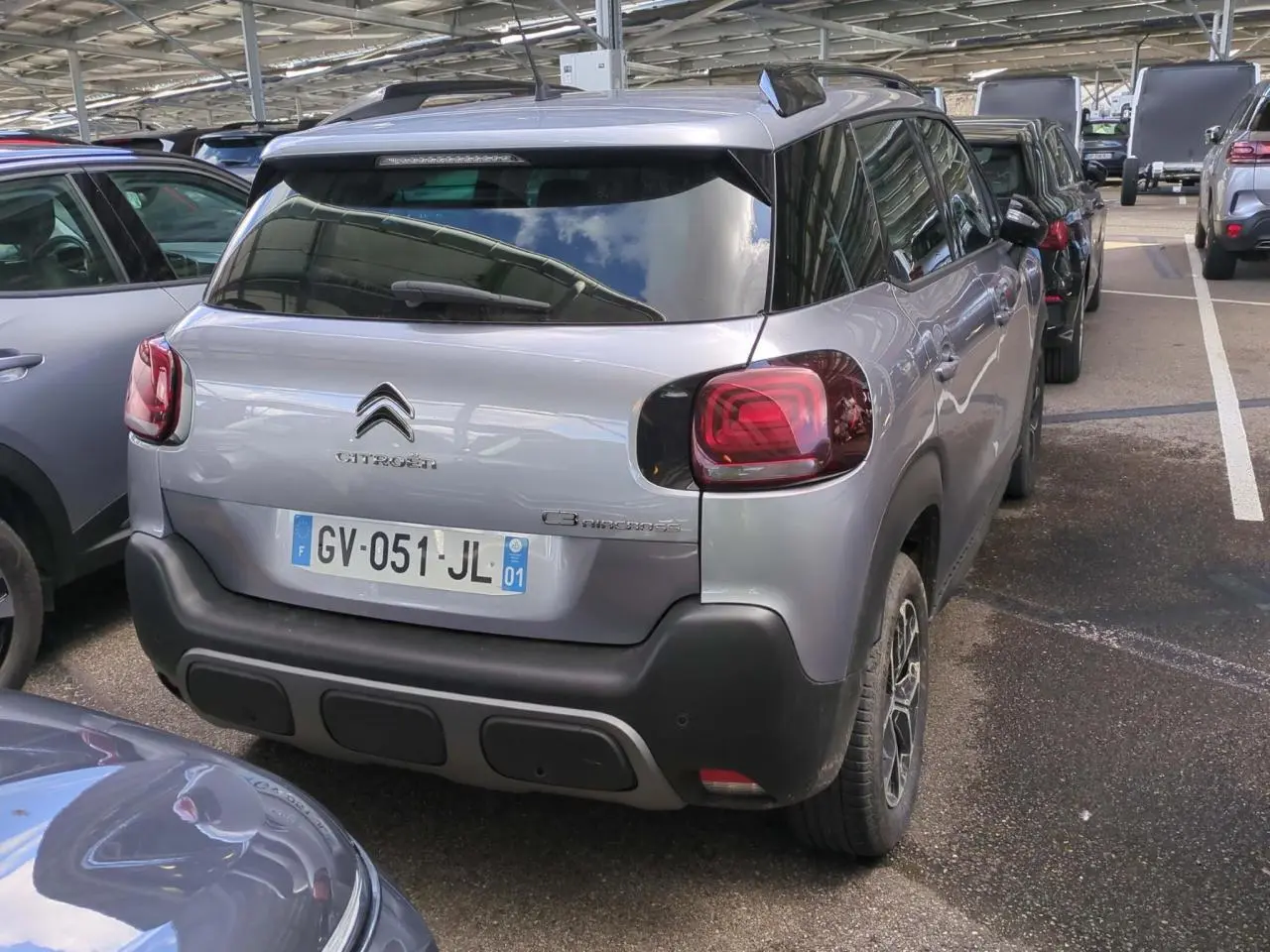 Vue 3/4 arrière droite d'un Citroën C3 Aircross gris foncé avec feux arrière rouges et jantes alliage 16 pouces.