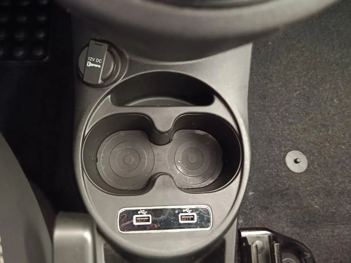 Vue rapprochée de la console centrale noire avec porte-gobelets et deux ports USB de la Fiat 500 Dolcevita blanche.