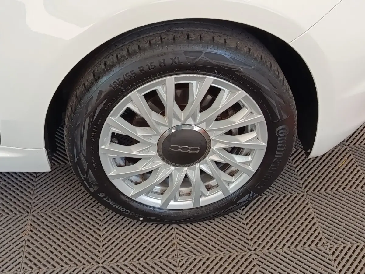 Gros plan sur la roue avant droite blanche d'une FIAT 500 Hybrid 2022 avec jante argentée à motifs fins.
