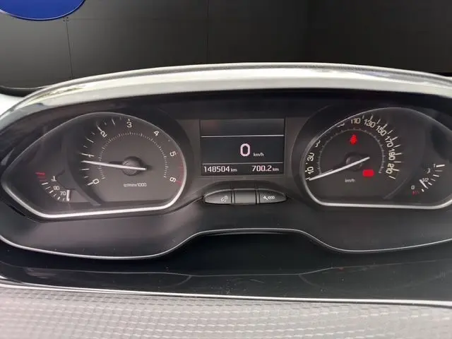 Vue rapprochée du tableau de bord de la Peugeot 208 gris platinium, affichant le compteur et l'écran digital central.