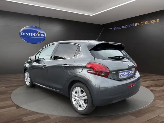 Peugeot 208 gris platinium vue 3/4 arrière droit dans un showroom avec jantes alliage et feux arrière LED.