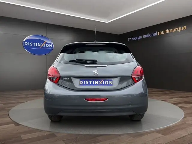 Vue arrière d'une Peugeot 208 gris platinium 2017 dans un showroom avec logo Distinxion en arrière-plan.