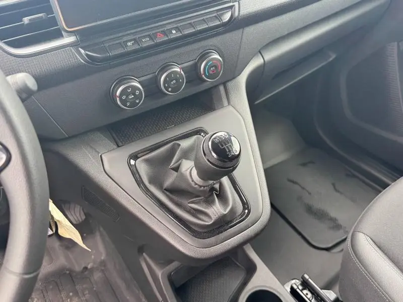 Vue intérieure centrée sur le levier de vitesses manuel noir du Renault Kangoo Van blanc avec commandes de climatisation.