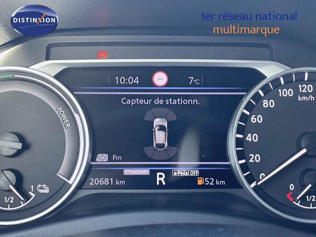 Tableau de bord du Nissan Juke gris squale métal 2024 montrant l'affichage du capteur de stationnement et le compteur kilométrique.