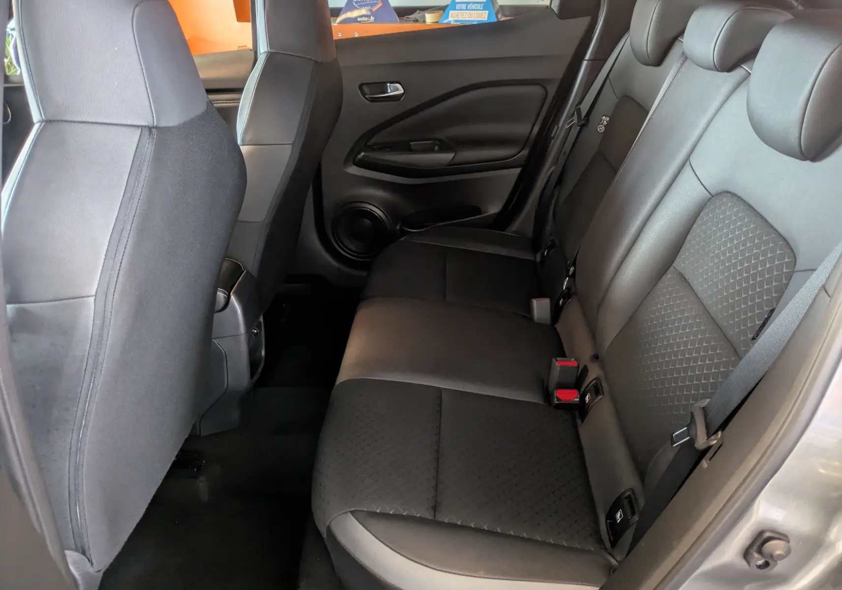 Vue intérieure côté droit des sièges arrière noirs en cuir et tissu du Nissan Juke 2024 gris squale metal.