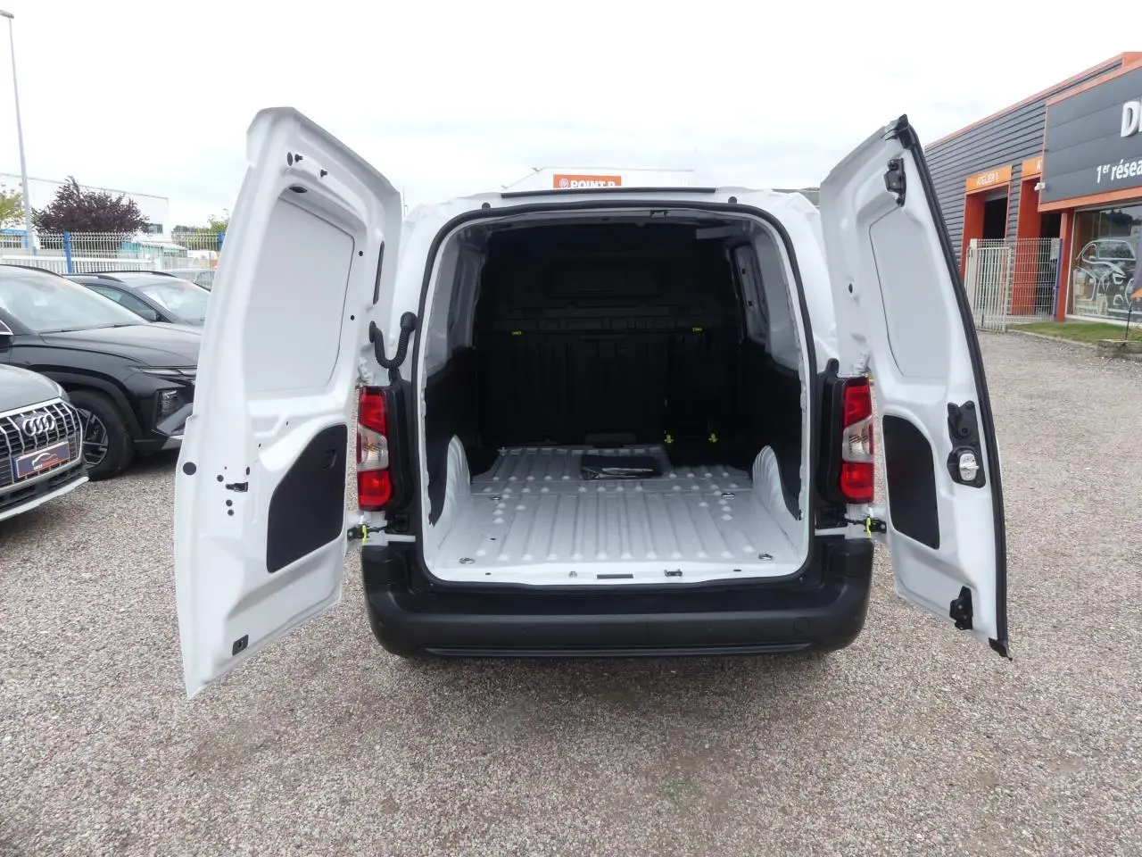 Vue arrière du Peugeot Partner blanc 2025 avec portes battantes ouvertes dévoilant l'espace de chargement vide.