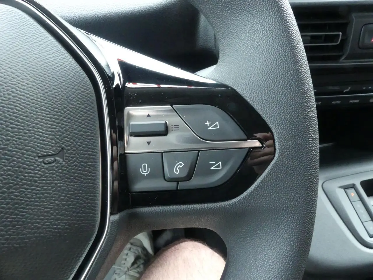 Gros plan sur les commandes multifonctions du volant côté gauche du Peugeot Partner blanc 2025.