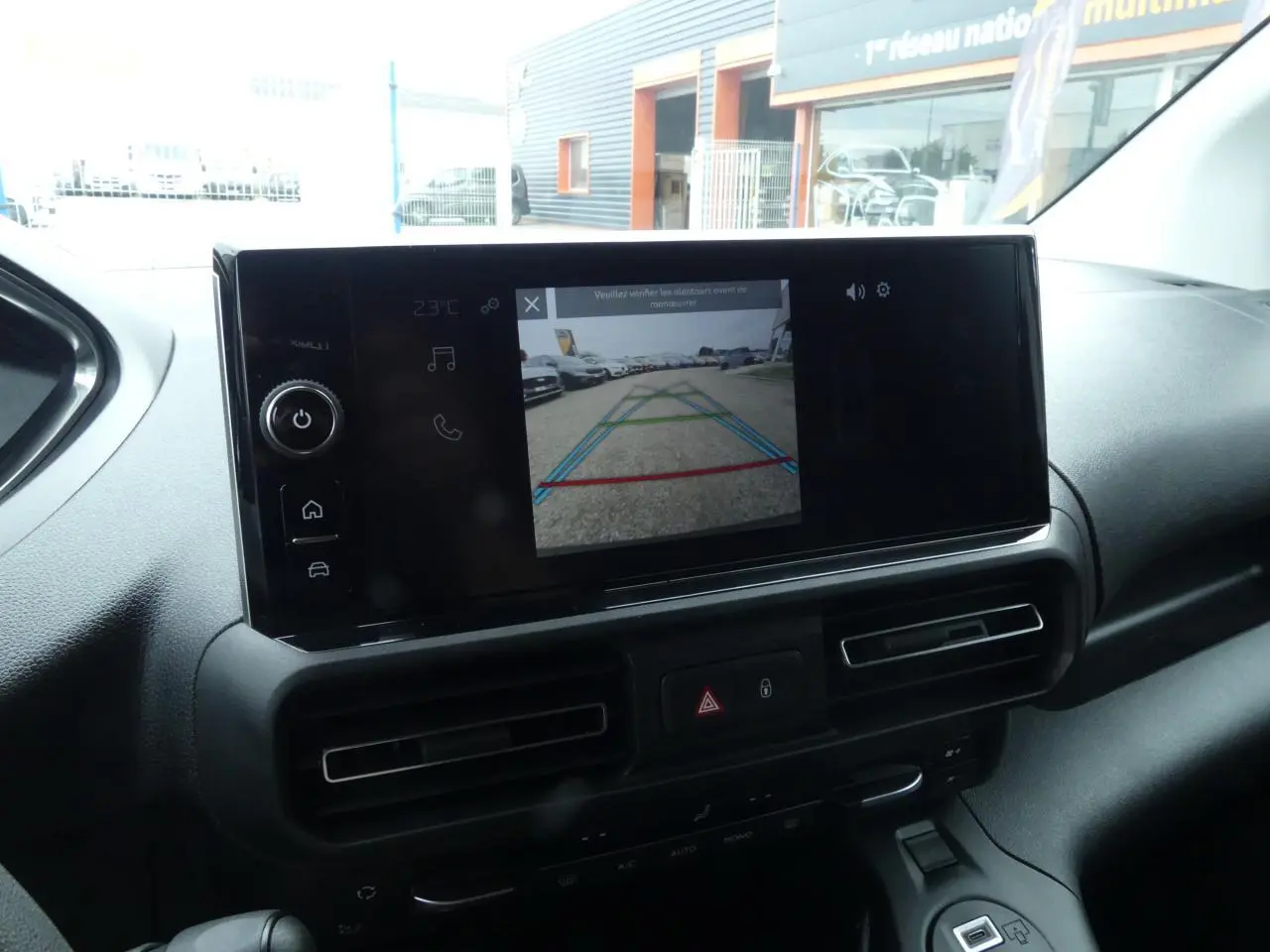 Écran tactile 10 pouces affichant la caméra de recul dans l'habitacle du Peugeot Partner blanc, vue de face.