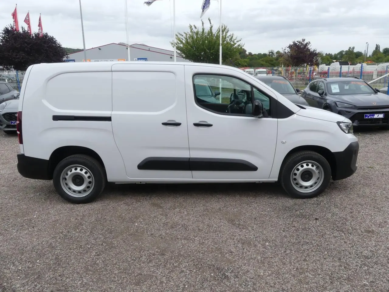 Profil latéral droit d'un utilitaire Peugeot Partner blanc avec porte coulissante et jantes tôles grises.
