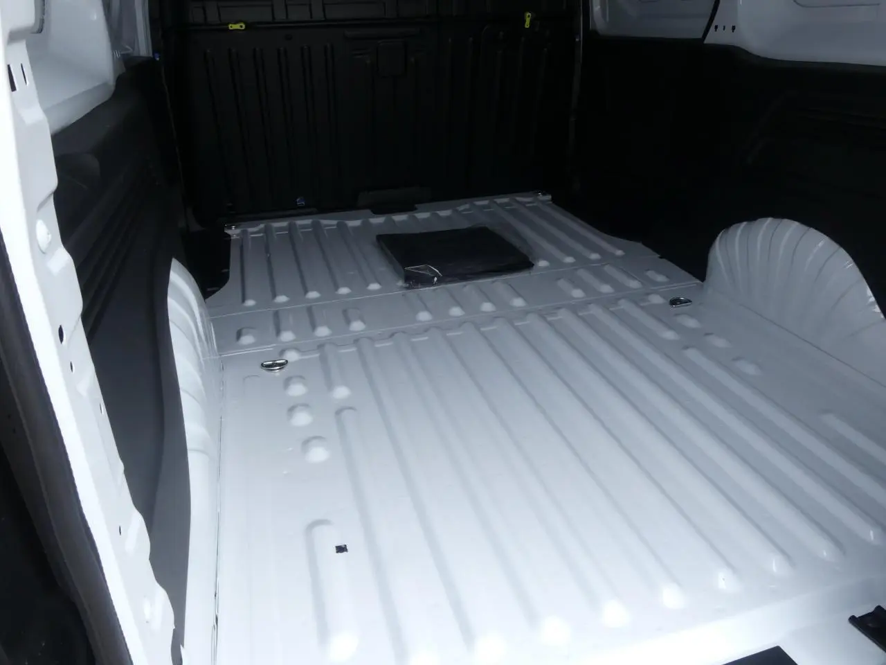 Vue intérieure du compartiment de chargement blanc du Peugeot Partner XL 2025, avec plancher métallique et anneaux d'arrimage.