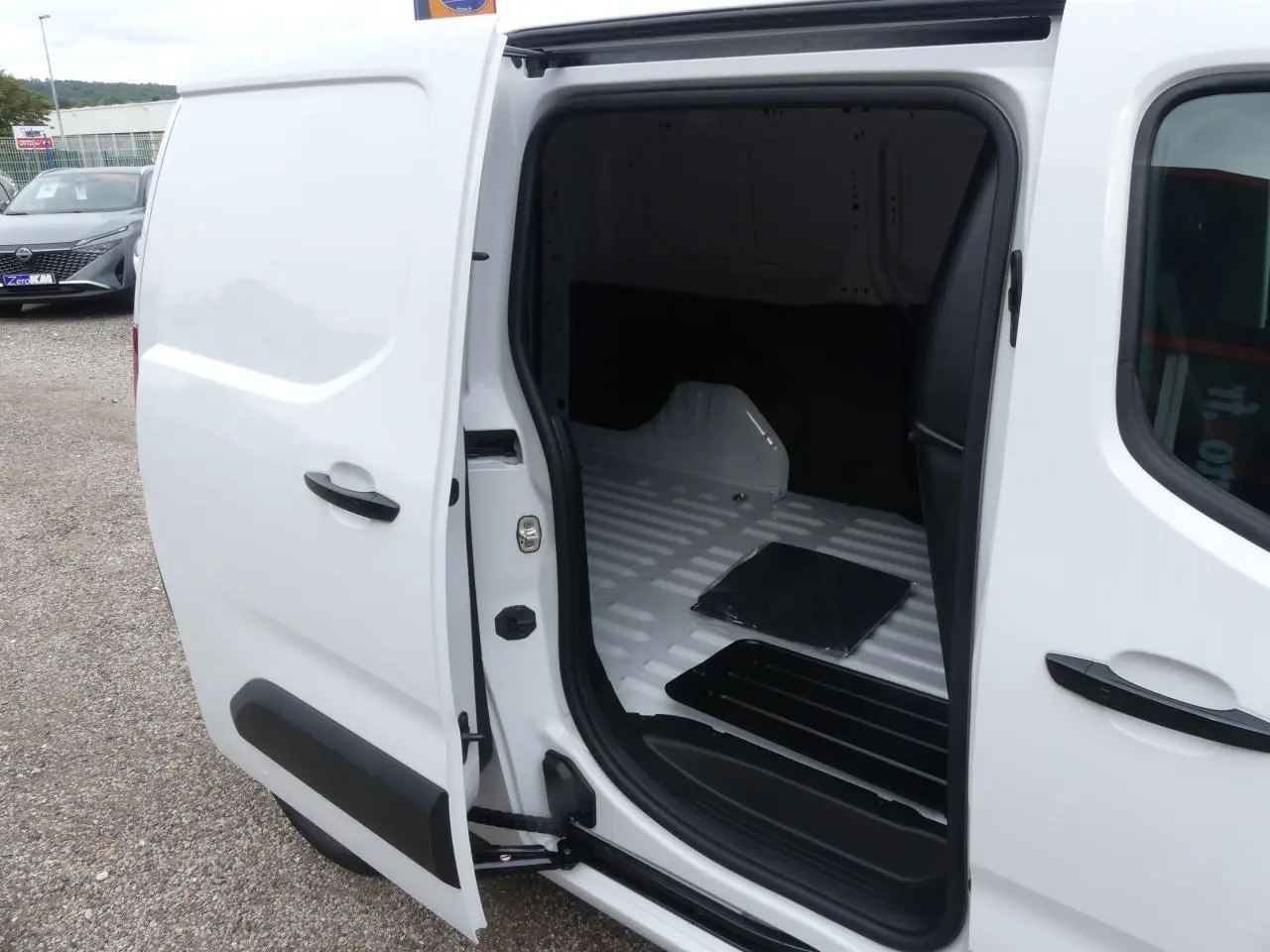 Vue latérale gauche du Peugeot Partner blanc 2025 avec porte coulissante ouverte montrant l'espace de chargement vide.