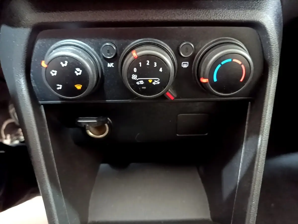 Gros plan sur les commandes de climatisation manuelle de la Dacia Sandero Confort TCe 90, tableau de bord noir.