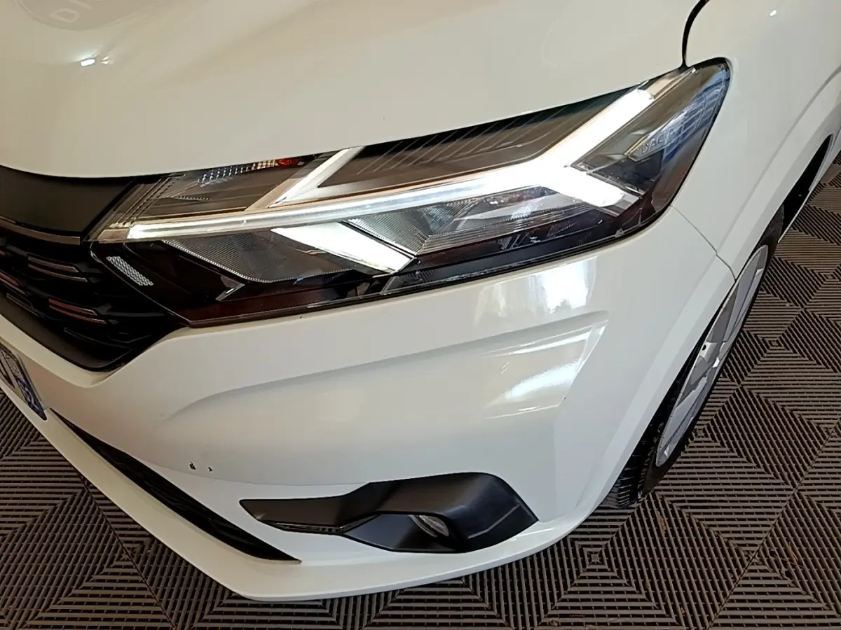 Gros plan sur l'avant droit blanc du Dacia Sandero 2022, mettant en valeur ses phares LED et antibrouillards.
