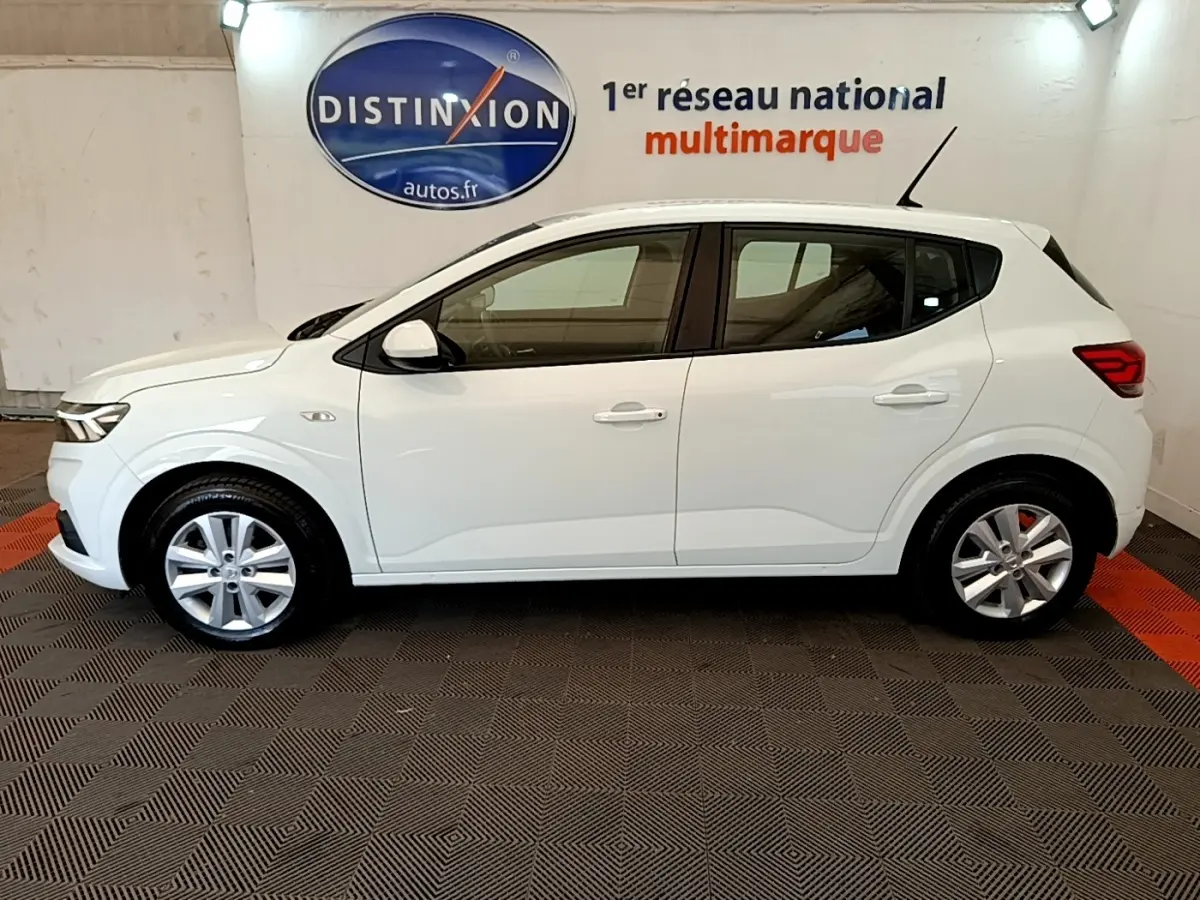 Vue de profil côté gauche d'une Dacia Sandero blanche 2022, avec jantes alliage et feux arrière LED visibles.