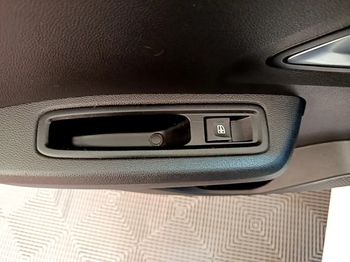Poignée intérieure de porte côté conducteur de Dacia Sandero blanc, avec bouton de commande de vitre électrique.