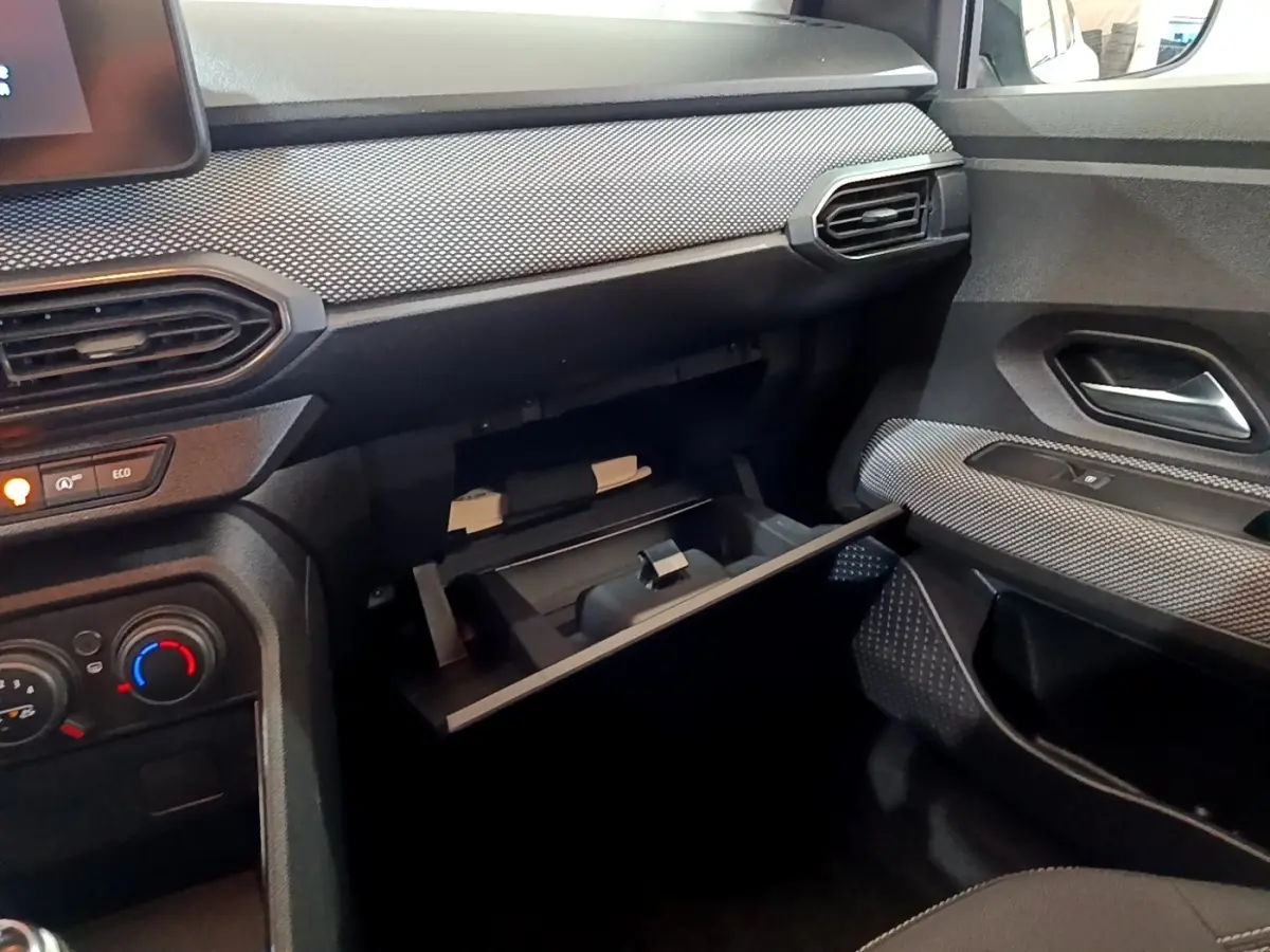 Intérieur de la Dacia Sandero Confort TCe 90 2022, vue côté passager avec boîte à gants ouverte et détails de la planche de bord.