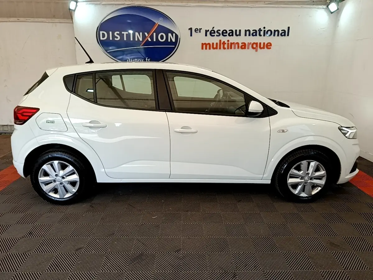 Profil côté gauche d'une Dacia Sandero Confort TCe 90 blanche 2022, avec jantes alliage et feux arrière visibles.