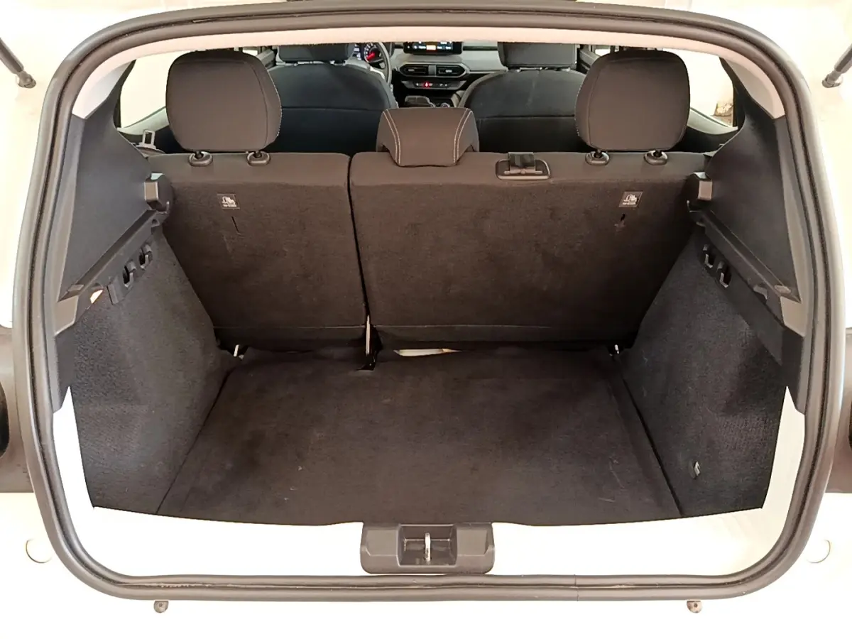 Coffre ouvert d'une Dacia Sandero blanc vue de l'arrière, montrant l'espace de chargement et la banquette arrière.