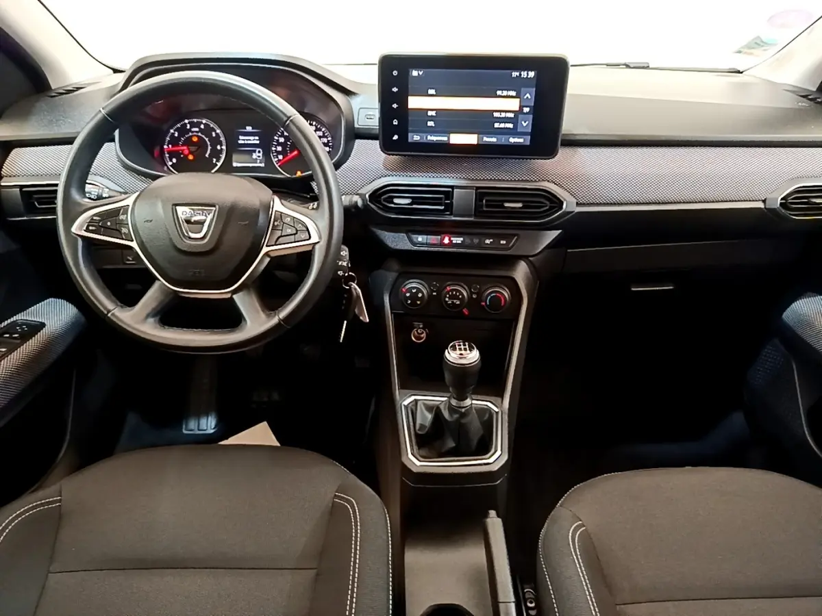 Vue intérieure frontale du tableau de bord et volant noir de la Dacia Sandero Confort TCe 90 avec écran tactile central.