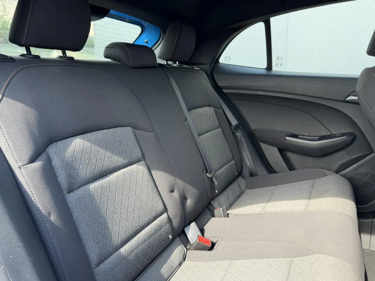 Vue latérale droite des sièges arrière en tissu noir de la MG3 1.5 Hybrid+ 195 Comfort, avec ceinture de sécurité visible.