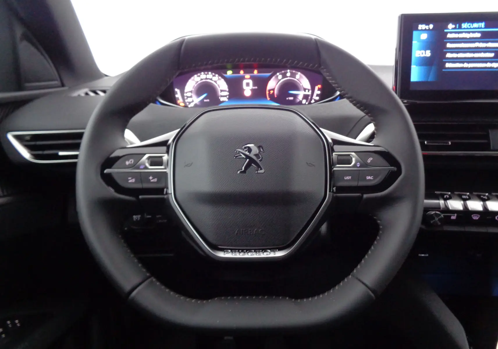 Vue frontale rapprochée du volant cuir noir du Peugeot 3008 2023 avec tableau de bord numérique et écran tactile.