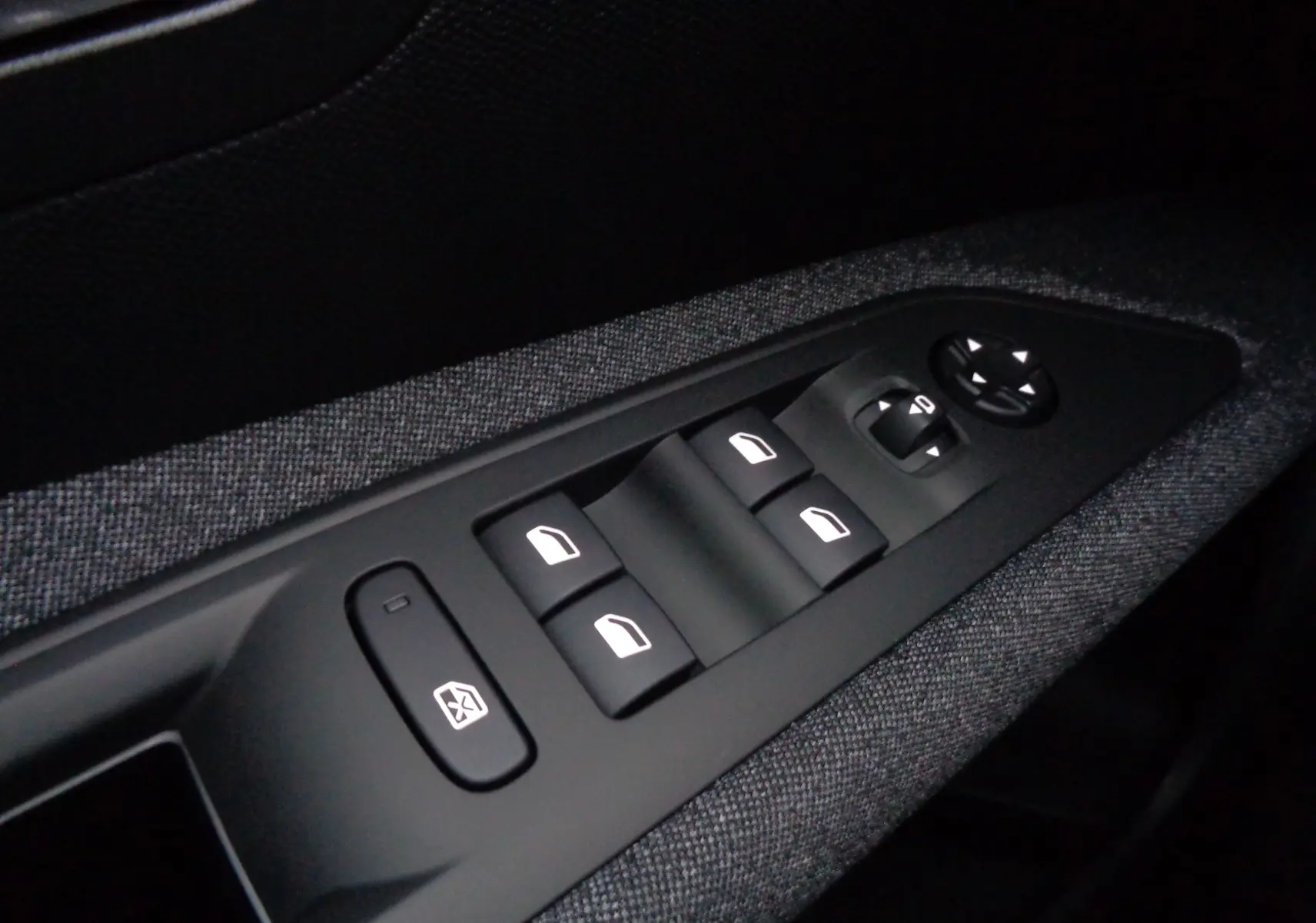 Gros plan sur les commandes des vitres électriques et rétroviseurs côté conducteur du Peugeot 3008 gris Artense 2023.